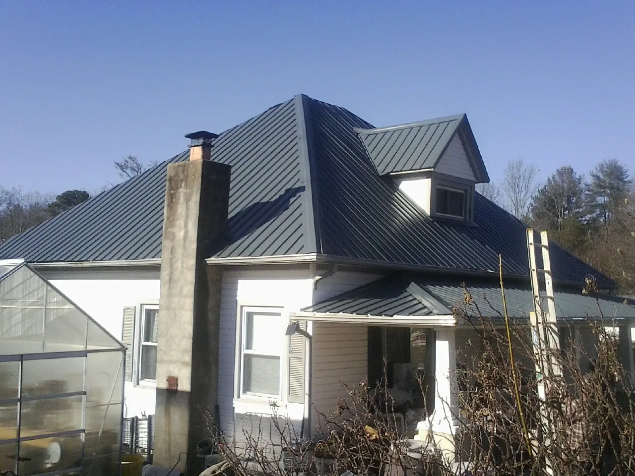 Dark blue standing seam metal roof on a white farmhouse with dormer — Slate & Tile Roof Repair by Roofing Brothers in Mekinock