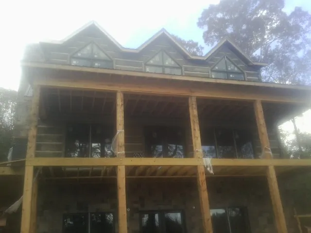 Dormers and porch framing on a large log home under construction — Roof Coating work by our crew in Mekinock
