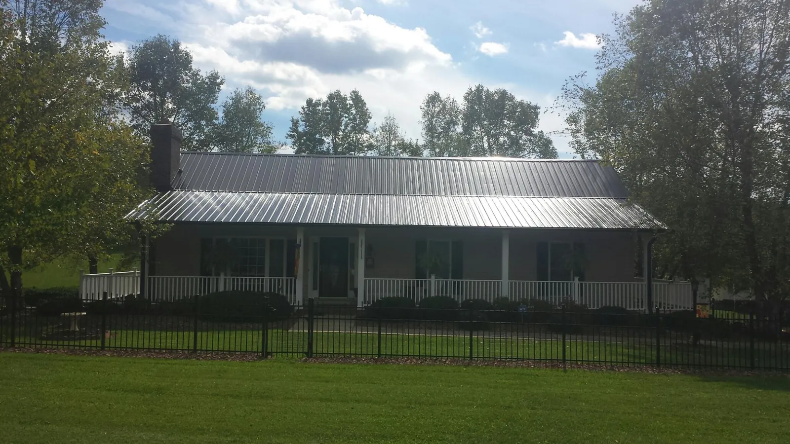 Gray metal roof on a brick ranch with a full width front porch — Gutter Guard Installation work by our crew in Mekinock