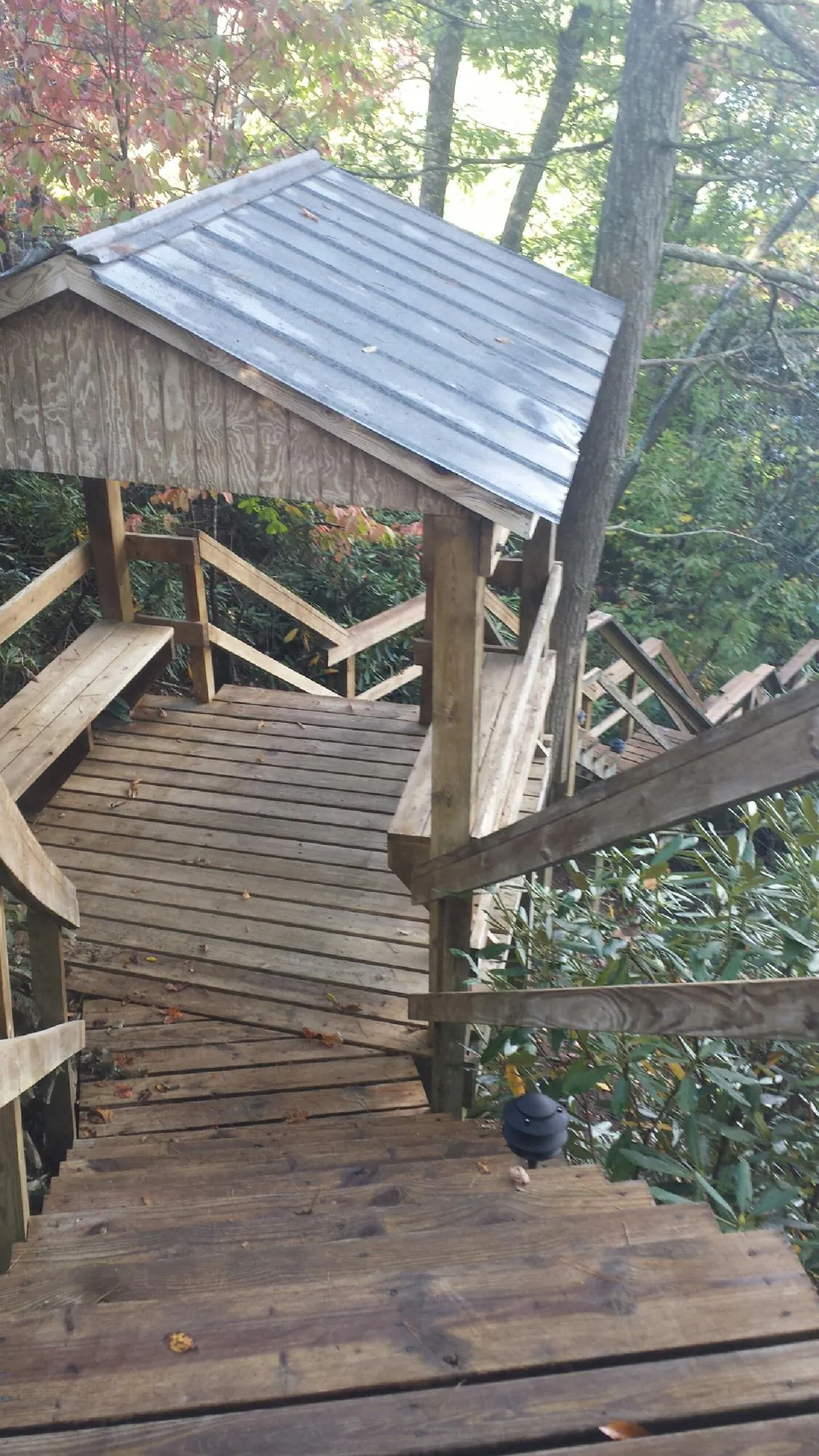 Metal roofed shelter over wooden steps on a wooded walkway — Skylight Repair & Installation work by our crew in Mekinock