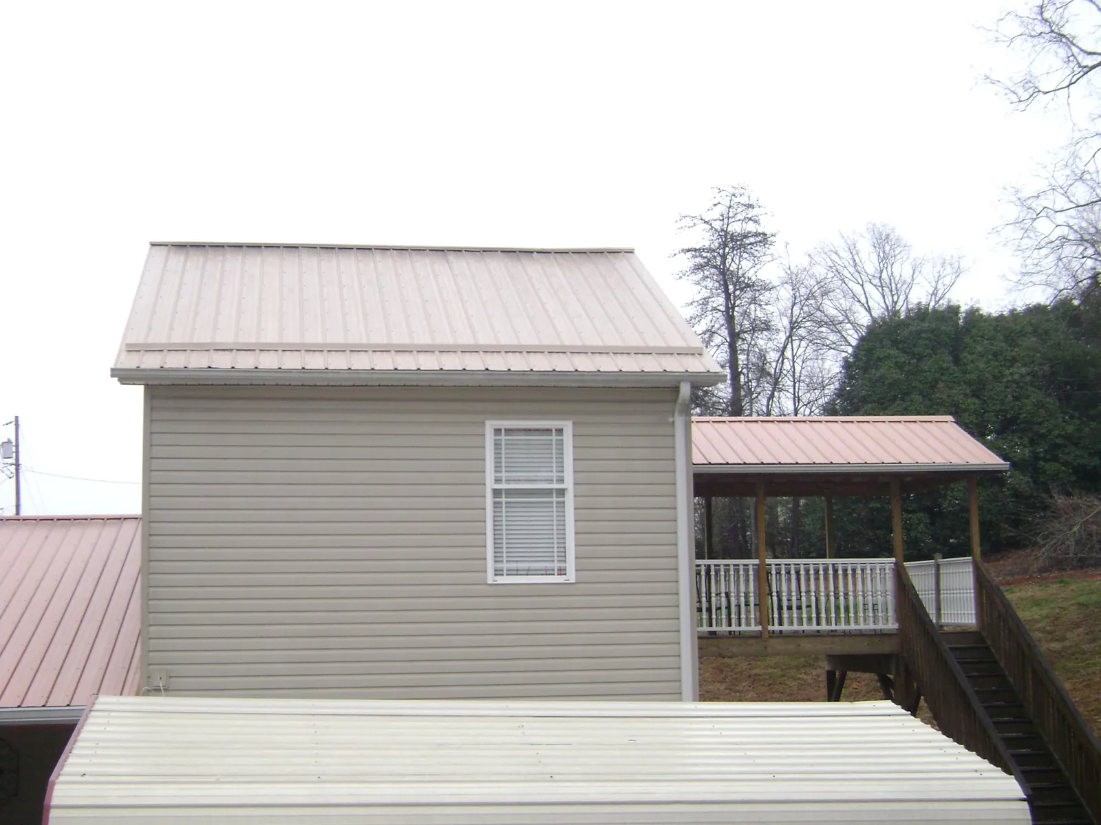 Tan metal roofs on a two story addition and attached porch, from a Roof Replacement job in Mekinock